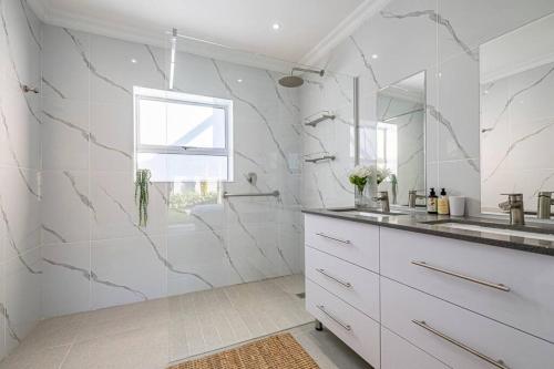 a white bathroom with a sink and a mirror at The River House - Addo Elephant Park in Gqeberha