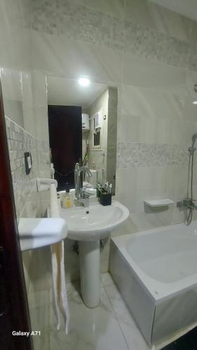 a bathroom with a sink and a tub and a sink and a mirror at Eamar tower 2 in Tanta