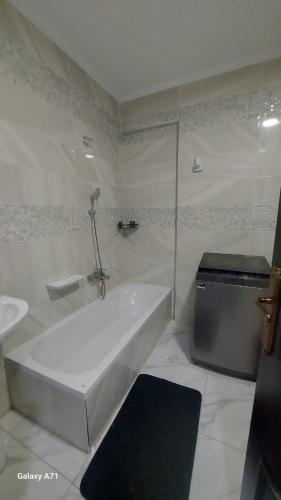 Baño blanco con bañera y lavamanos en Eamar tower 2, en Tanta