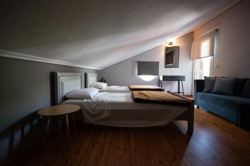 ein Schlafzimmer mit einem Bett und einem blauen Sofa in der Unterkunft Kaiafas Lake Hotel in Kaiafas
