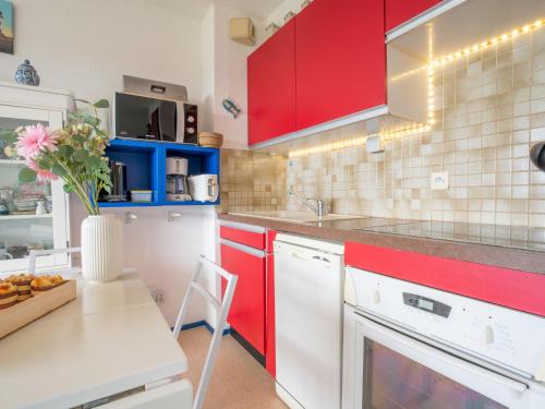 eine Küche mit roten Schränken und einem Tisch mit einer Blumenvase in der Unterkunft Apartment Plein Sud-1 by Interhome in Quiberon