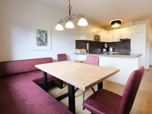 una sala da pranzo e una cucina con tavolo in legno e sedie viola di Apartment Edith - IST100 by Interhome a Imst