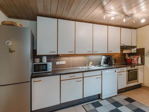a kitchen with white cabinets and a refrigerator at Holiday Home Bergfried - FUC150 by Interhome in Fusch an der Glocknerstraße