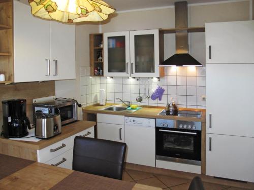 TimmelにあるHoliday Home Kleine Möwe by Interhomeのキッチン(白いキャビネット、コンロ付)
