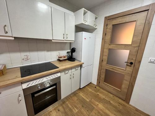 uma cozinha com armários brancos e uma porta de madeira em Casa Rural Chincha em Tragacete