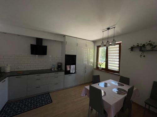 a kitchen with a dining room table and a kitchen with white cabinets at Apartament Rybical in Ryn