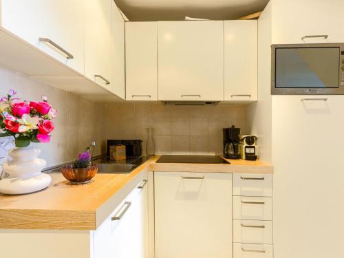 a kitchen with white cabinets and a vase of flowers at Apartment Villa M-Thérèse Promenade Anglais by Interhome in Nice