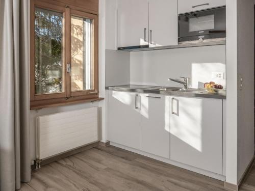 une cuisine avec des placards blancs et une fenêtre dans l'établissement Apartment Appartementhaus Zurschmitten 12 by Interhome, à Riederalp