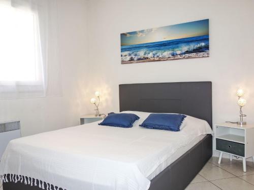 une chambre avec un grand lit blanc avec des oreillers bleus dans l'établissement Apartment Beau Rivage by Interhome, à Carqueiranne