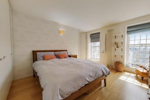 a white bedroom with a large bed with orange pillows at Apt - Sleeps 4 - Pets Ok - Roof Garden in London