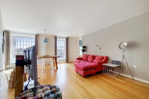 a living room with a red couch and a tv at Apt - Sleeps 4 - Pets Ok - Roof Garden in London
