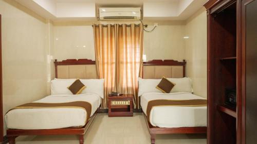 a hotel room with two beds and a window at HOTEL YUVRAJ SIGNATURE in Mysore