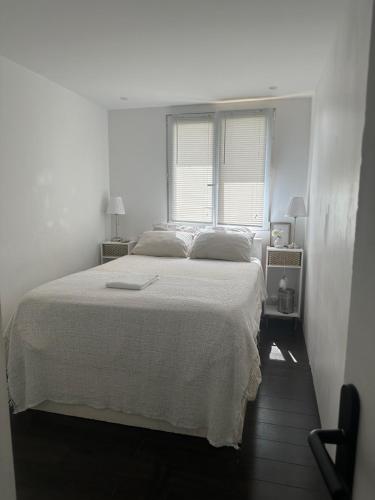 een witte slaapkamer met een bed en een raam bij Location de chambre privée dans résidence privée,parking gratuit , 1 minute du tramway, à 9 minute du centre ville, accessible à plusieurs transports in Nice