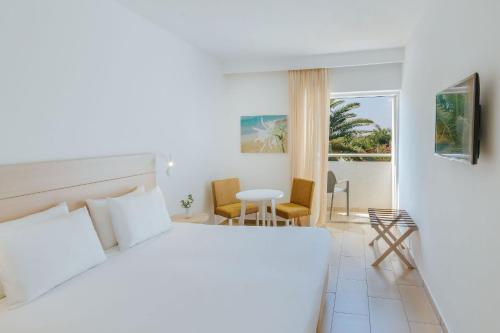 um quarto com uma cama, uma mesa e cadeiras em Nissi Park Hotel em Agia Napa
