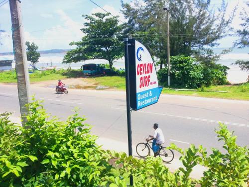 a man riding a bike next to a sign on a street at Ceylon Surf Guest and Restaurant in Weligama