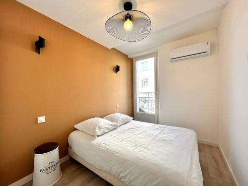 une chambre avec un lit blanc et un ventilateur de plafond dans l'établissement Emma - 4/6 pers NEUF- Hyper centre Clim Terrasse, à Saint-Raphaël