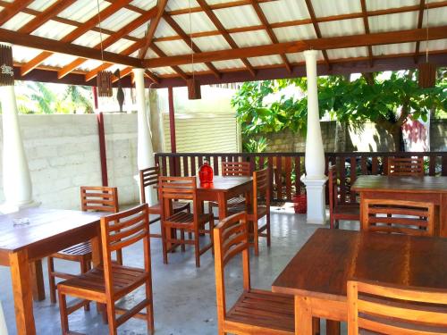 a restaurant with wooden tables and chairs under a pergola at Ceylon Surf Guest and Restaurant in Weligama