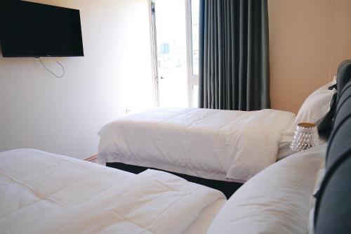 a hotel room with two beds and a flat screen tv at Ufo Rooms City Center in Tirana