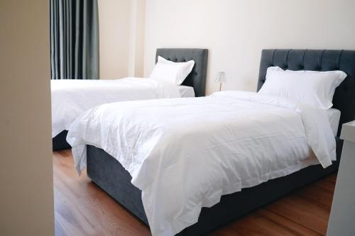 two beds with white blankets and pillows in a bedroom at Ufo Rooms City Center in Tirana