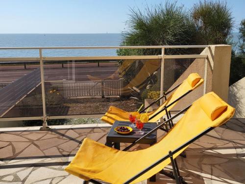 d'un balcon avec des chaises jaunes et une table donnant sur l'océan. dans l'établissement Holiday Home La Grande Côte bis by Interhome, à Saint-Palais-sur-Mer