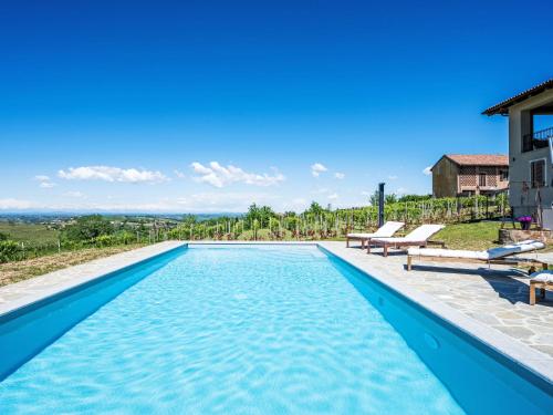 a swimming pool with two benches next to a house at Apartment La Rosa by Interhome in Costigliole dʼAsti
