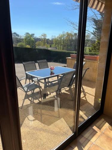 - une table et des chaises sur une terrasse à l'extérieur d'une fenêtre dans l'établissement Bel appartement avec piscine, à Saint-Geniès