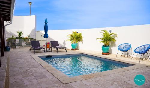 a swimming pool in a patio with chairs and tables at Villa Noëlyne in Le Robert