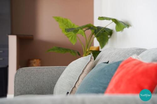 a couch with two pillows and a plant on it at Villa Noëlyne in Le Robert