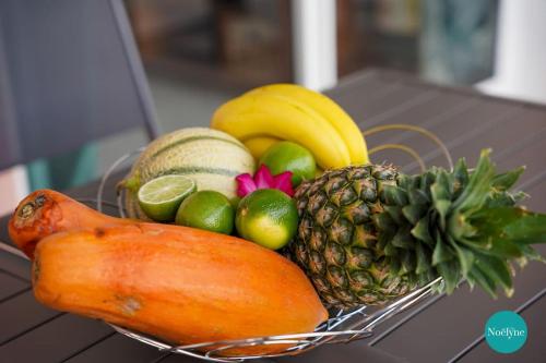 a basket of fruit and vegetables on a table at Villa Noëlyne in Le Robert