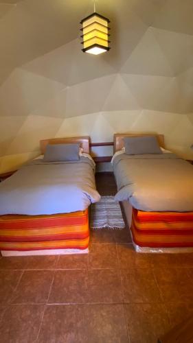 two beds sitting next to each other in a room at San Pedro Domos in San Pedro de Atacama