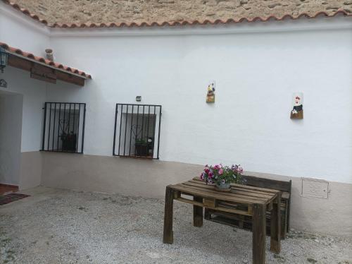 ein Tisch mit Blumen neben einer weißen Wand in der Unterkunft Cueva la Trapera in Benamaurel