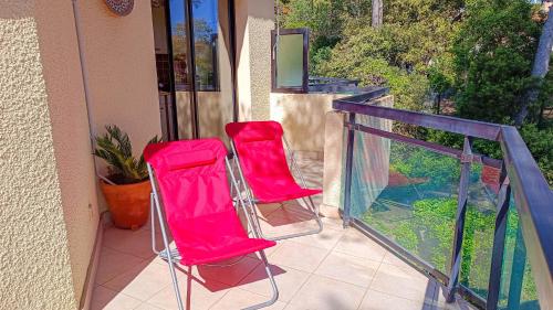 - deux chaises rouges assises sur un balcon dans l'établissement VILLA REIALA Saint-Raphaël, à Saint-Raphaël
