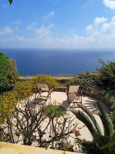 two chairs sitting on a patio overlooking the ocean at Dammuso Libeccio in Pantelleria