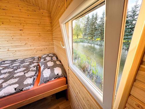 a bedroom with a window in a log cabin at Maringotka na kraji rybníka 
