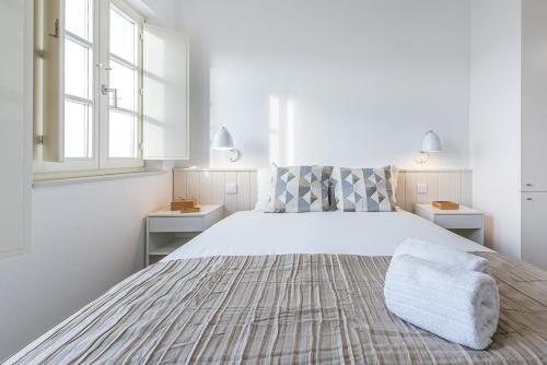 a white bedroom with a large bed and two windows at GuestReady - Port Studio 2 in Bandeira