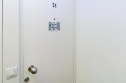 une porte blanche avec un panneau sur elle dans l'établissement GuestReady - Ribeira Apt in Porto center, à Porto