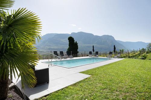 a swimming pool with chairs and a view of mountains at Bacchushof Apartment Chardonnay in Termeno