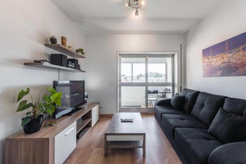ein Wohnzimmer mit einem Sofa und einem TV in der Unterkunft GuestReady - Never Say Never in Porto