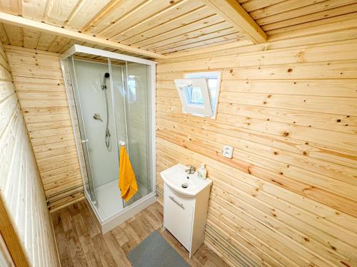 uma casa de banho em madeira com um chuveiro e um lavatório em Maringotka na kraji rybníka 
