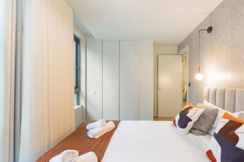 a bedroom with a large white bed with towels on it at GuestReady - Khaki Roof in Vila Nova de Gaia