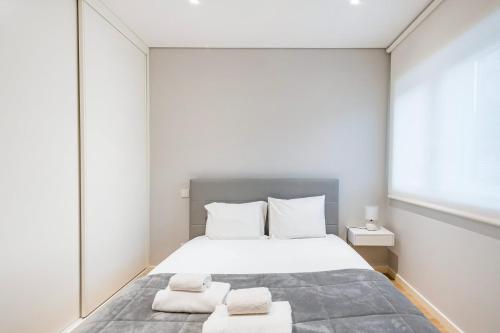 1 dormitorio con 1 cama blanca grande y 2 toallas en GuestReady - Ideal Getaway minutes from Porto, en Gondomar