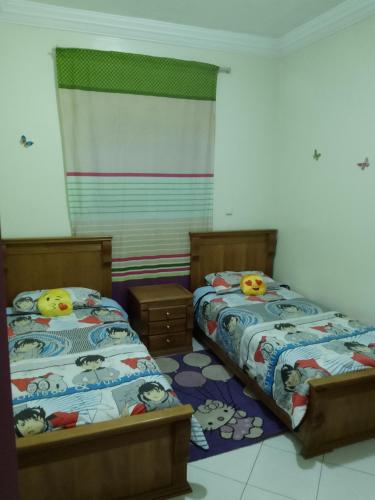 dos camas sentadas una al lado de la otra en una habitación en Appartement de vacances, en Agadir