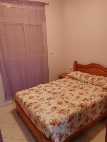 a bedroom with a bed with a floral comforter at Appartement de vacances in Agadir