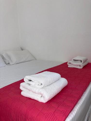 ein Bett mit weißen Handtüchern auf einer roten Decke in der Unterkunft Marena 2 in Makry Gialos