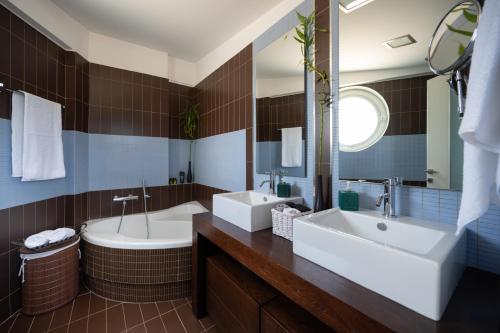 a bathroom with two sinks and a tub and a mirror at 3 Palm Villa in Chalkida