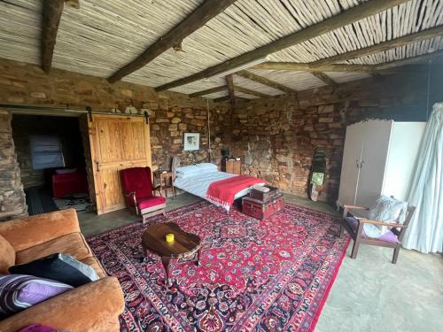 a bedroom with a bed and a couch and a rug at Kwaggaskop Farm Kliphuis in Dullstroom