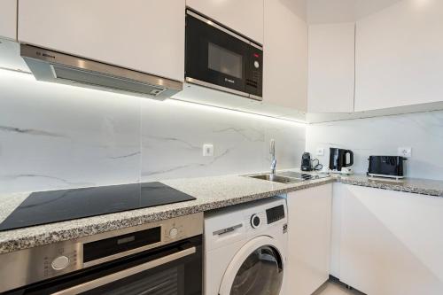a kitchen with a washing machine and a microwave at GuestReady - Cozy place in Matosinhos in Matosinhos