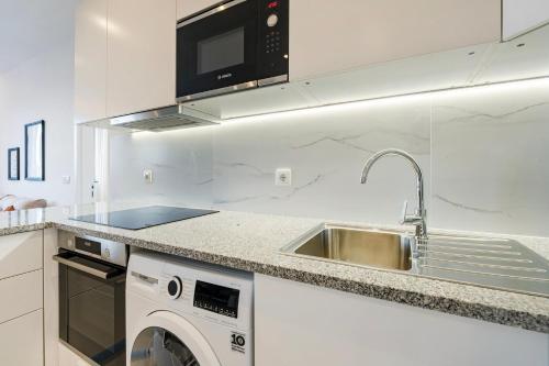a kitchen with a sink and a washing machine at GuestReady - Cozy place in Matosinhos in Matosinhos