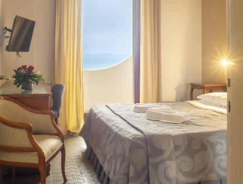 a hotel room with a bed and a chair and a window at Hotel Sinuessa Terme in Mondragone