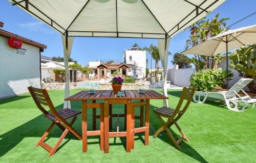 Una mesa de madera y dos sillas con sombrillas. en Gorgeous Home In Terrasini, en Terrasini